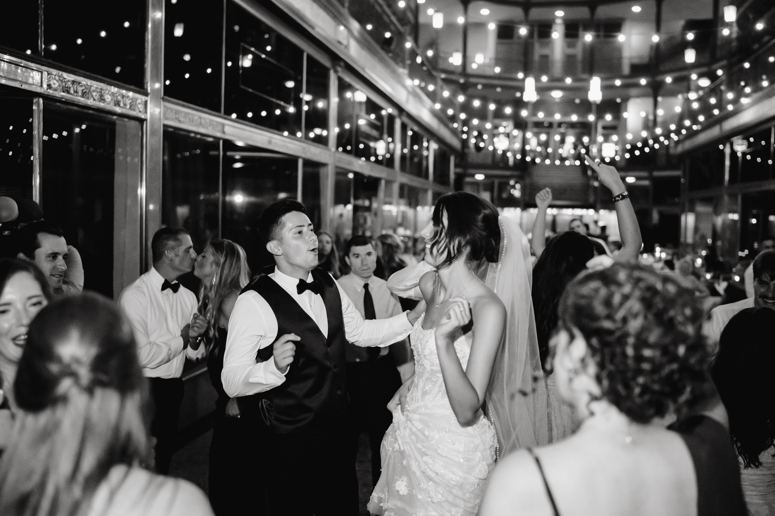 Newlyweds dancing with guests in black and white
