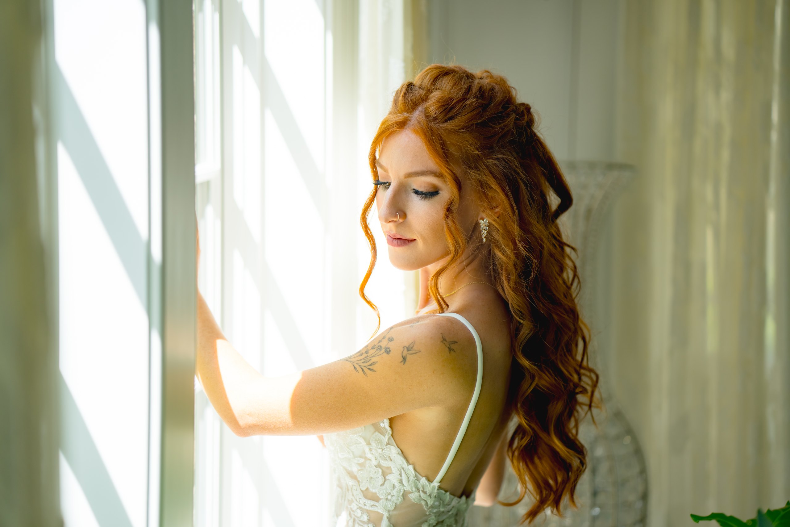 A bride standing by a sunlit window