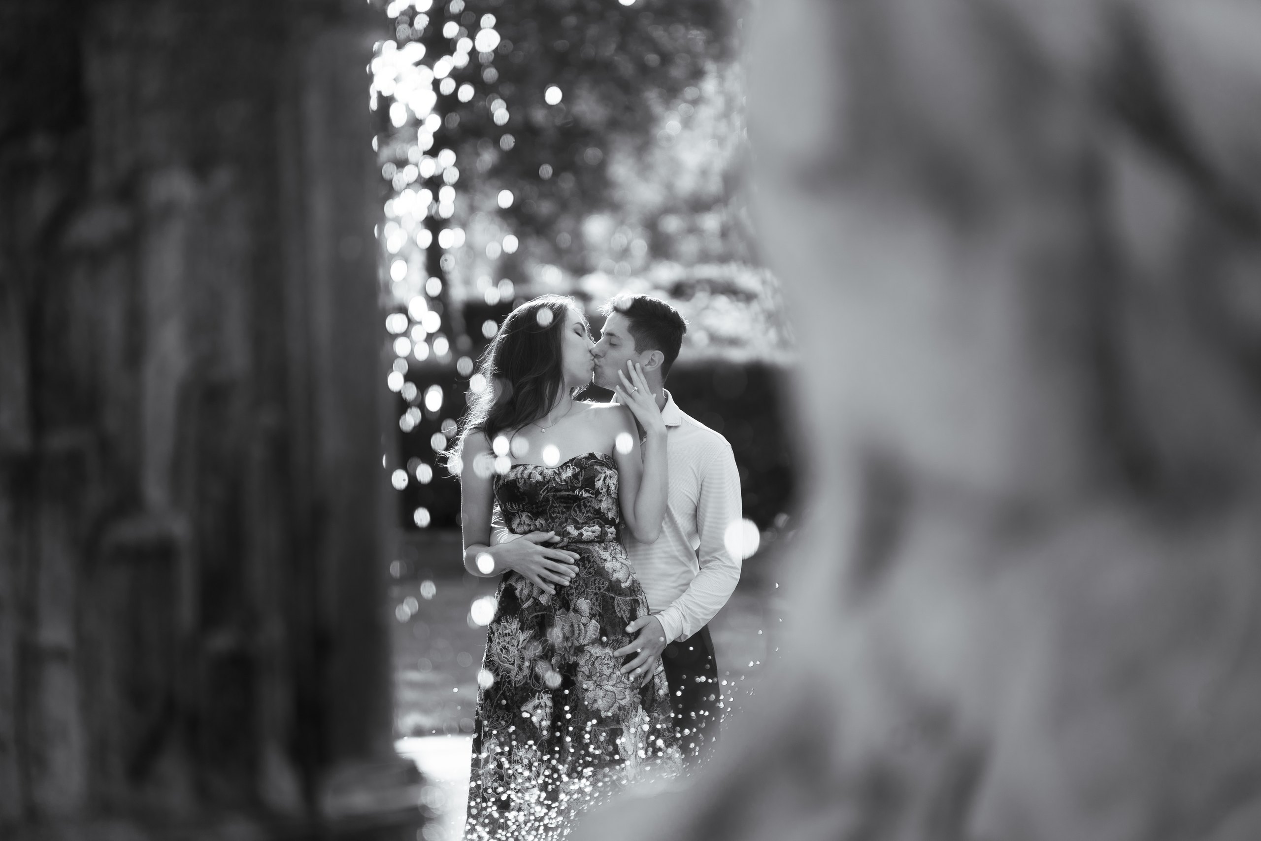 A couple kissing beside a fountain in black and white